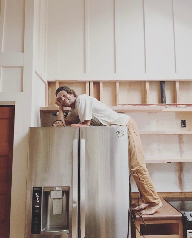 Jason leaning over a refrigerator while fitting custom kitchen shelving
